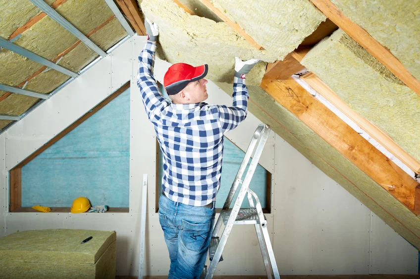 Man installing thermal roof insulation layer using mineral woo